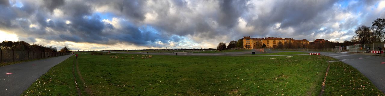 sky, the way forward, cloud - sky, grass, road, cloudy, diminishing perspective, cloud, vanishing point, transportation, landscape, panoramic, building exterior, street, road marking, field, tranquil scene, tranquility, footpath, nature