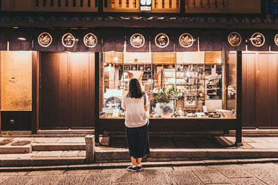 Rear view of woman standing at store