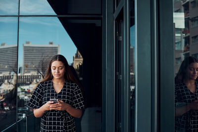 Woman standing by window in city