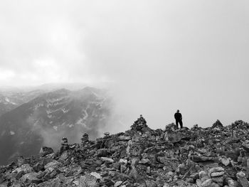 Low angle view of man standing on mountain against cloudy sky