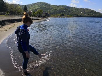 Woman splashing water while standing in lake