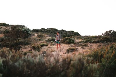 Rear view of person standing on land against sky