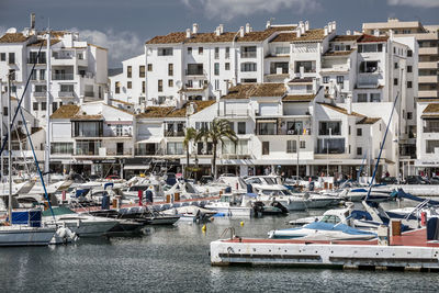 Boats moored in harbor by buildings in city