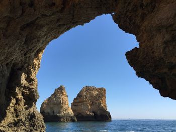 Rock formations in sea against clear sky