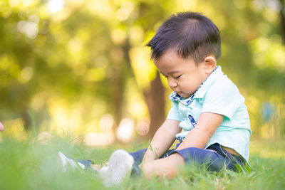 Cute baby boy sitting on grassy land in park