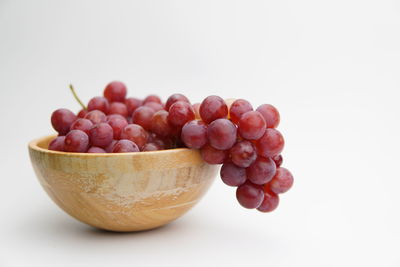 Close-up of grapes in bowl against white background