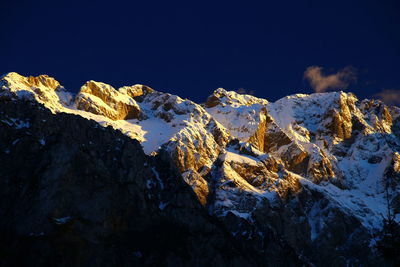 Low angle view of snowcapped mountain against blue sky