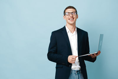 Portrait of businessman standing against blue background