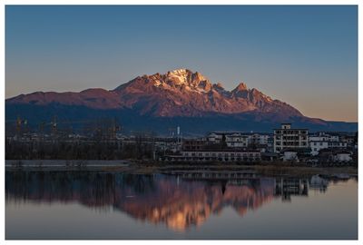 Reflection of buildings in lake against clear sky