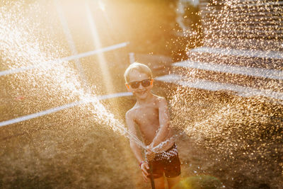 Happy boy playing with garden hose