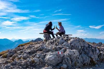 People sitting on rock against mountains