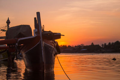 Silhouette boats in sea against orange sky