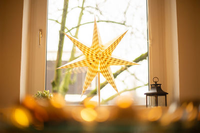 Close-up of yellow decoration hanging against window