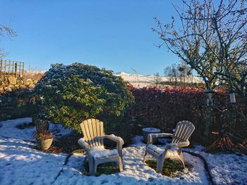 Chairs on landscape against clear blue sky