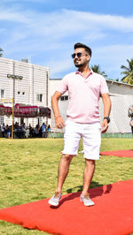 Full length of young man wearing sunglasses standing against sky