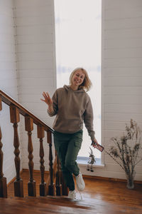 Portrait of a smiling young woman standing against railing