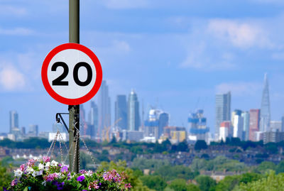 Close-up of 20mph road sign against london skyline