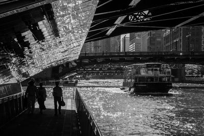 Silhouette people walking on footbridge over river