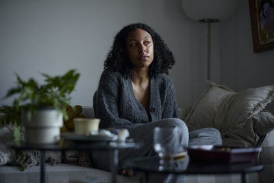 Pensive young woman sitting at home