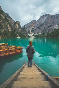 Rear view of man looking at lake against mountain