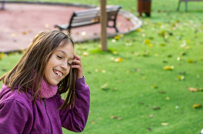 Smiling girl with hand in hair standing on land at park