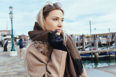 Young woman standing against sky in city