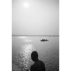 Rear view of man looking at sea against sky