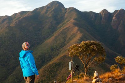 Rear view of woman standing on mountain against sky