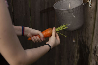 Cropped hand of woman holding and washing carrot 
