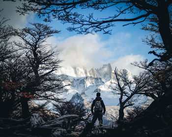 Rear view of man standing on mountain against sky