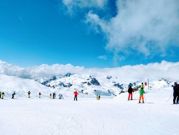 Group of people on snowcapped mountain against sky