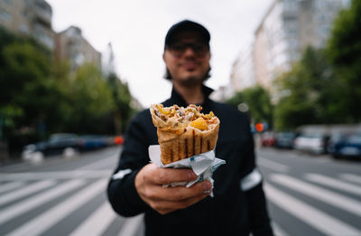 Man holding kebab sandwich wrap on street