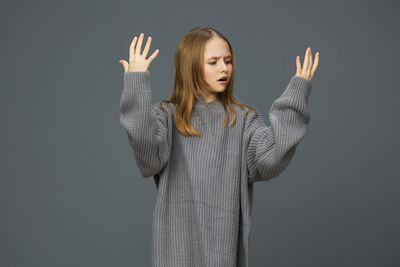 Portrait of young woman standing against black background