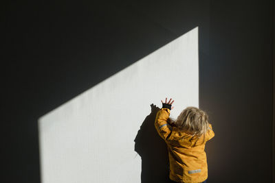 Rear view of woman standing against wall