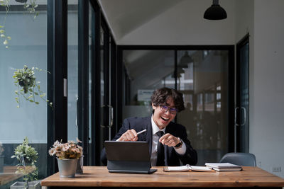 Side view of young man using mobile phone while standing in office