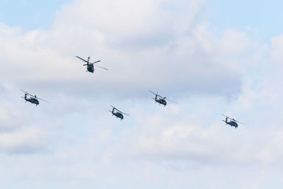 Low angle view of helicopters flying against sky