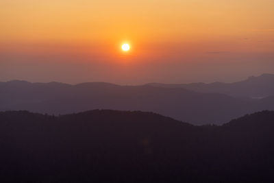 Scenic view of silhouette mountains against orange sky