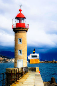 Lighthouse by sea against sky