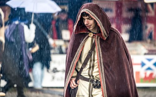 Smiling man wearing hooded cape during rainfall