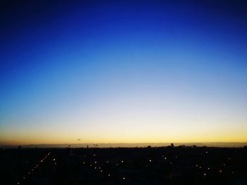 Illuminated cityscape against clear sky during sunset