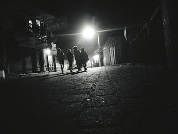 Rear view of people walking in illuminated tunnel