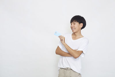 Smiling young woman standing against white background