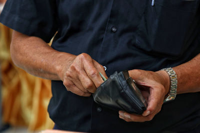 Midsection of man holding wallet