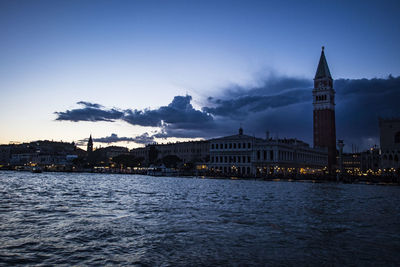 City at waterfront against cloudy sky