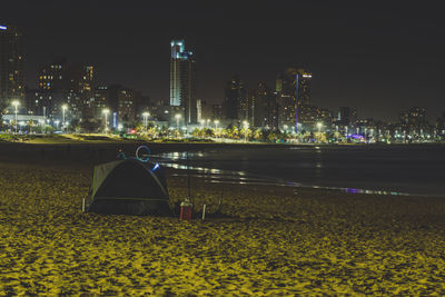 Illuminated city by buildings against sky at night