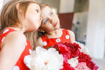 Close-up of girl holding flowers while standing by mirror reflection