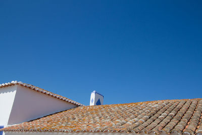 Low angle view of house roof against clear blue sky