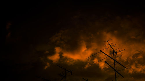 Low angle view of silhouette communications tower against sky at sunset