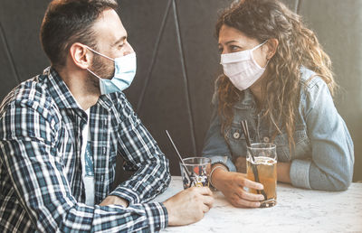 Couple wearing masks enjoying drinks at restaurant