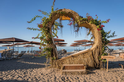 Heart shaped structure decorated with plants and flowers at sandy beach
